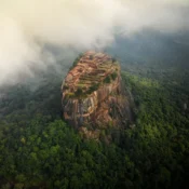 Sigiriya Rock Fortress surrounded by green jungle and mist