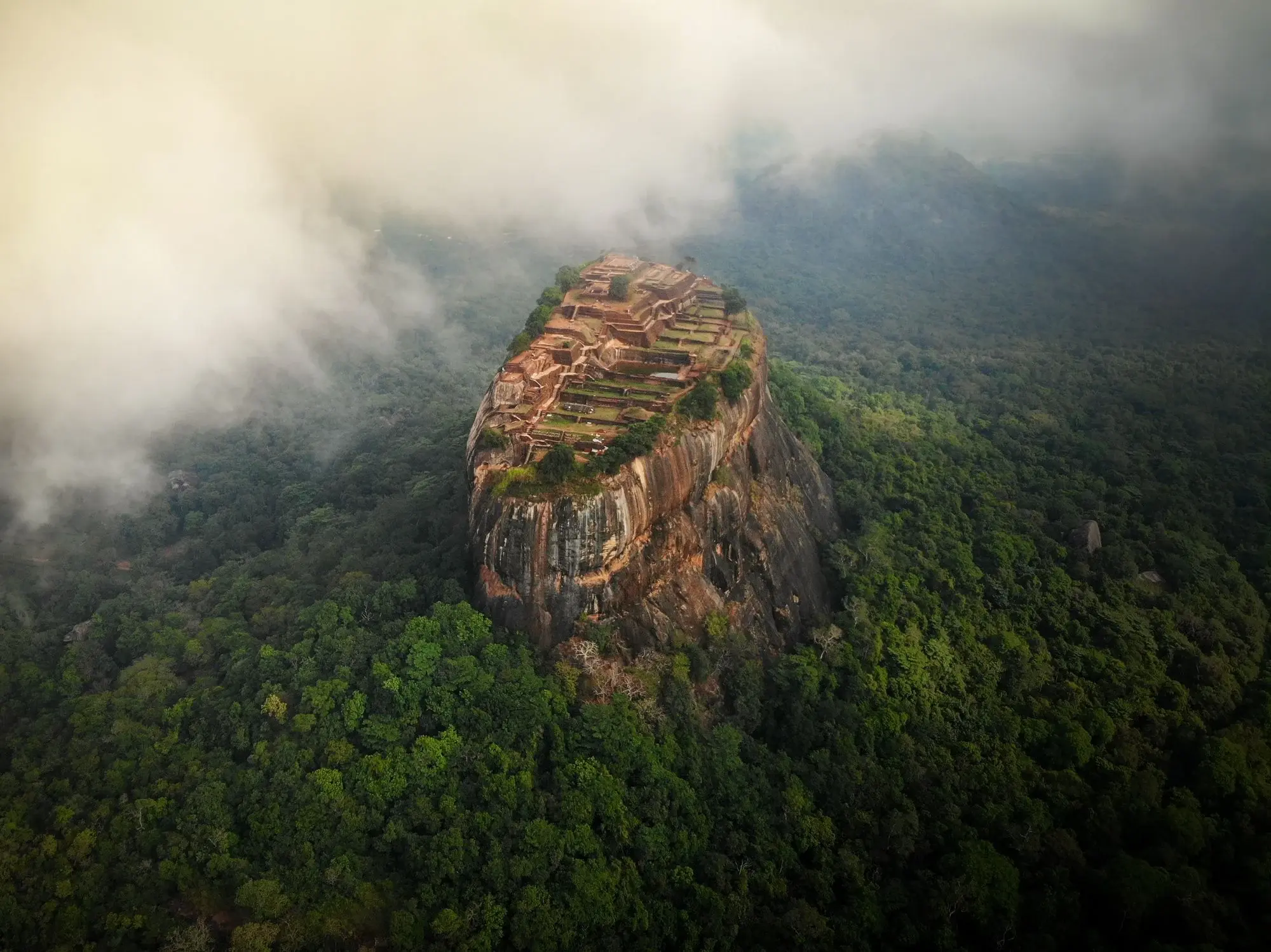 Sigiriya Rock Fortress surrounded by green jungle and mist